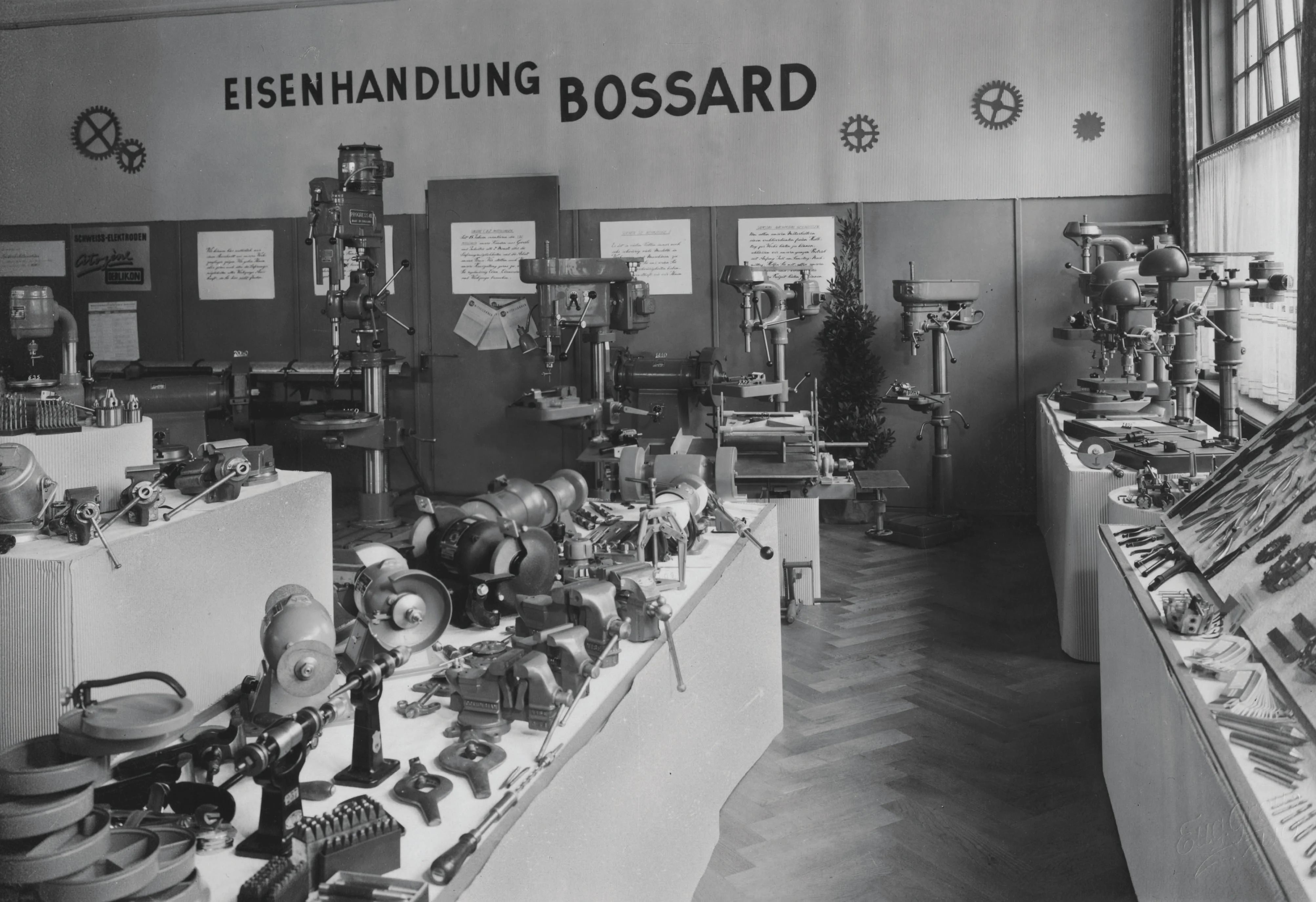 一张1930年代Bossard五金店的黑白老照片,店内摆满了各种工具和设备。